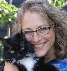 Pet health coach holding tuxedo cat close to face